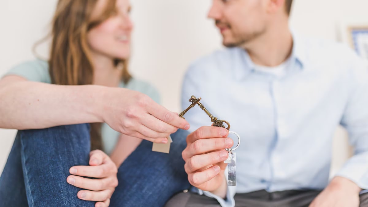 A young couple sitting together exchanging keys, symbolizing new home ownership